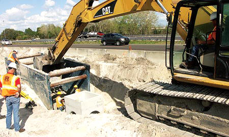 A pipe crew installs storm drainage on Rangers I-4 interchange project at SR-46. Crew members include Foreman Pat Monroe, Hoe Operator Ira Wilson, and near the structure, Eliu Vasquez and Jorge Barragan. (Photo by Carl Thiemann)