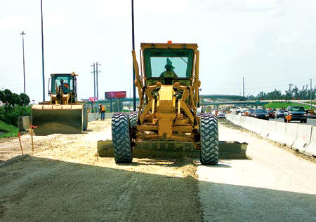 Among the many Ranger Construction workers on a major design-build I-595 expansion project underway in Broward County are Grader Operator Jacquelin Guerrier, Loader Operator Dufrenne Dues, and Roller Operator Dominique Simon (in the background with shovel). (Photo by Carl Thiemann)