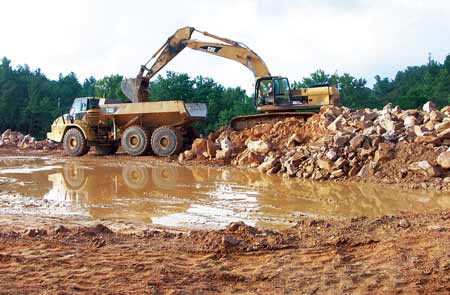 Hoe Operator Jerry Blair loads excess material into an articulated haul truck driven by Evelyn Jarrell on V&Gs East Beckley (WV) Bypass project. (Photo by Carl Thiemann)