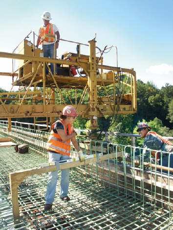 Bridge Foreman Ruben Adkins operates a deck screed on V&Gs East Beckley Bypass project as Shelly Phillips and Manolo Rico ensure guides are correctly positioned prior to concrete being poured. (Photo by Carl Thiemann)