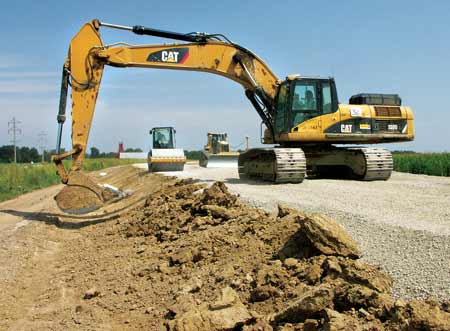 Hoe Operator Bryan Bell dresses the slope alongside a railroad and roadway bed at Deer Run Mine, while Dozer Operator Ed Chaiffins spreads and levels the rock, and Roller Operator Robert Spencer compacts it. (Photo by Carl Thiemann)